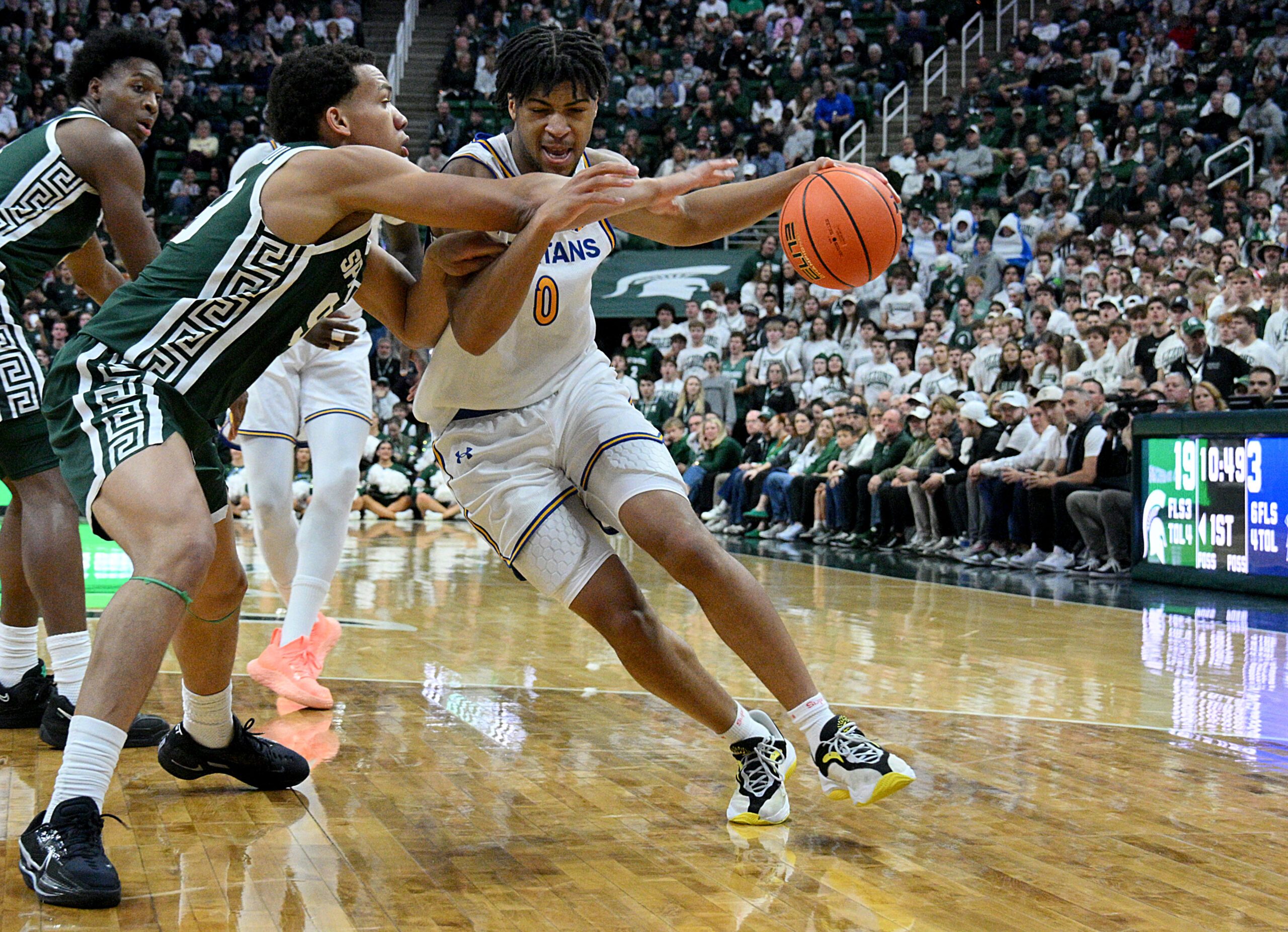 Nov 13, 2025; East Lansing, Michigan, USA;  San Jose State Spartans guard Colby Garland (0) dribbles against Michigan State Spartans guard Divine Ugochukwu (99) during the first half at Jack Breslin Student Events Center. Mandatory Credit: Dale Young-Imagn Images