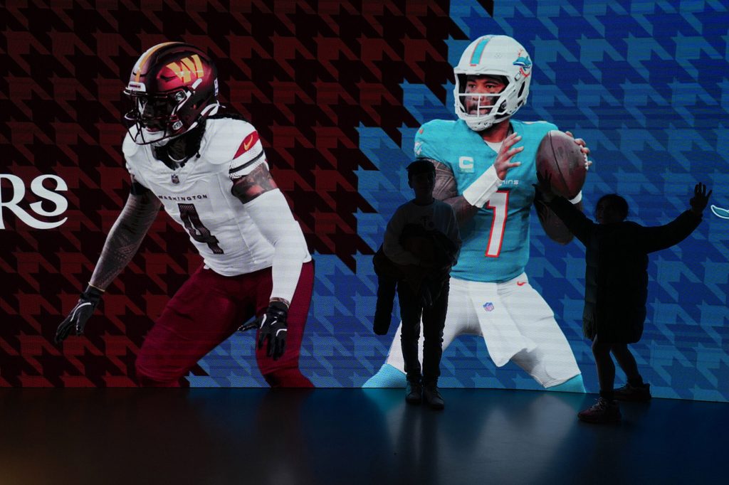 Nov 14, 2025; Madrid, Spain; Fans pose with images of Washington Commanders linebacker Frankie Luvu (4) and Miami Dolphins quarterback Tua Tagovailoa (1) at Santiago Bernabeu Stadium. Mandatory Credit: Kirby Lee-Imagn Images