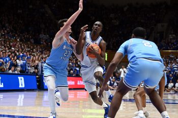 Nov 14, 2025; Durham, North Carolina, USA; Duke Blue Devils forward Dame Sarr (7) drives to the basket as Indiana State Sycamores forward Ian Scott (23) defends during the second half at Cameron Indoor Stadium. Mandatory Credit: Rob Kinnan-Imagn Images