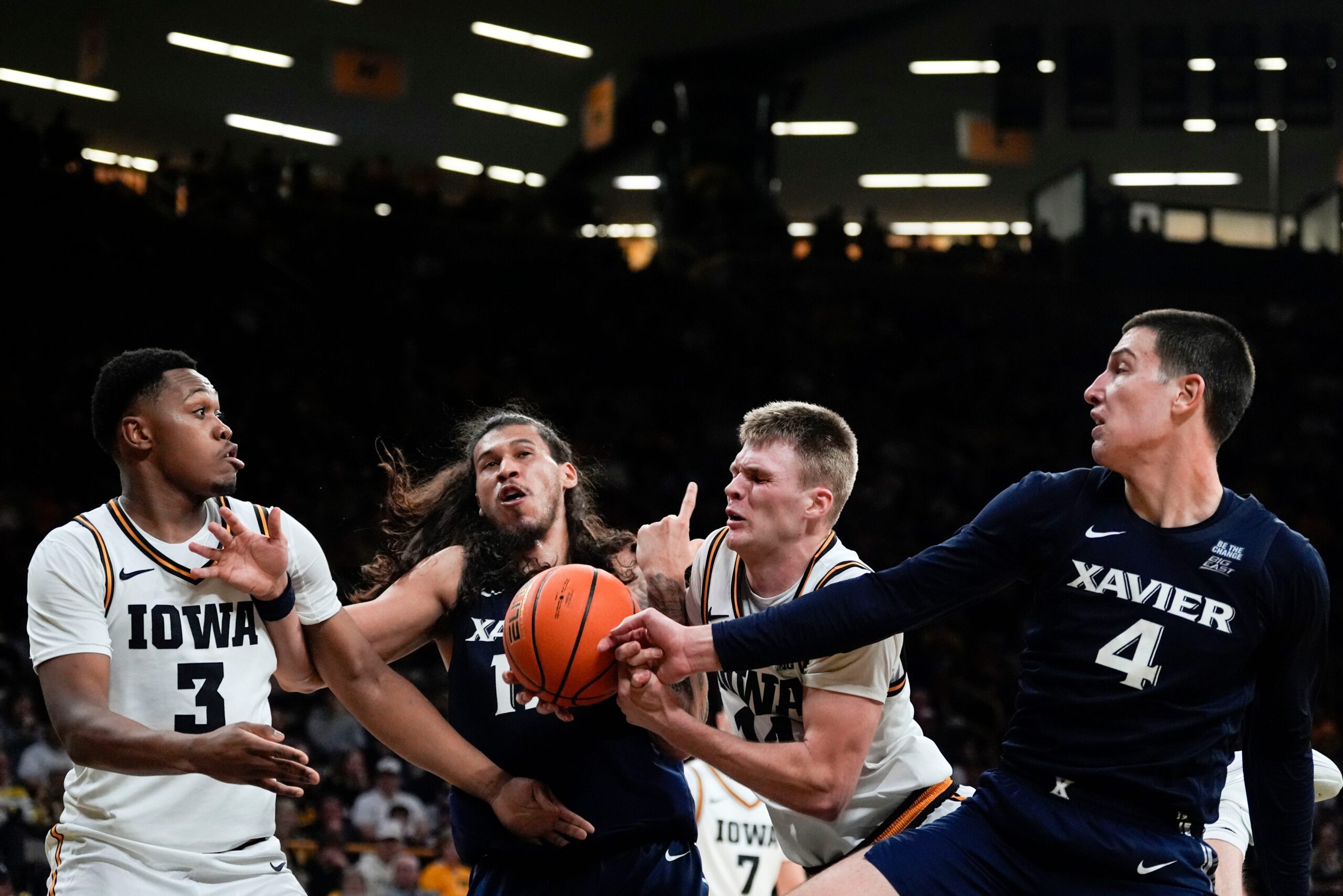Iowa forward Cam Manyawu (3), Xavier forward Tre Carroll (12), Iowa guard Bennett Stirtz (14) and Xavier forward Filip Borovicanin (4) reach for a rebound Nov. 14, 2025 at Carver-Hawkeye Arena in Iowa City, Iowa.