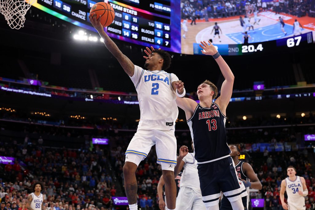 Nov 14, 2025; Inglewood, California, USA; UCLA Bruins guard Donovan Dent (2) goes to the basket past Arizona Wildcats center Motiejus Krivas (13) during the second half of the Hall of Fame Series game at Intuit Dome. Mandatory Credit: Kiyoshi Mio-Imagn Images