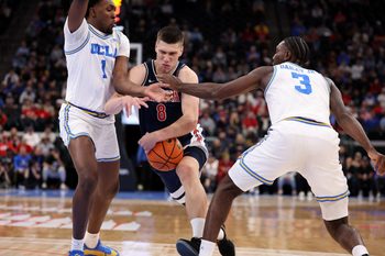 Nov 14, 2025; Inglewood, California, USA;  Arizona Wildcats forward Ivan Kharchenkov (8) drives between UCLA Bruins center Xavier Booker (1) and forward Eric Dailey Jr. (3) during the first half of the Hall of Fame Series game at Intuit Dome. Mandatory Credit: Kiyoshi Mio-Imagn Images