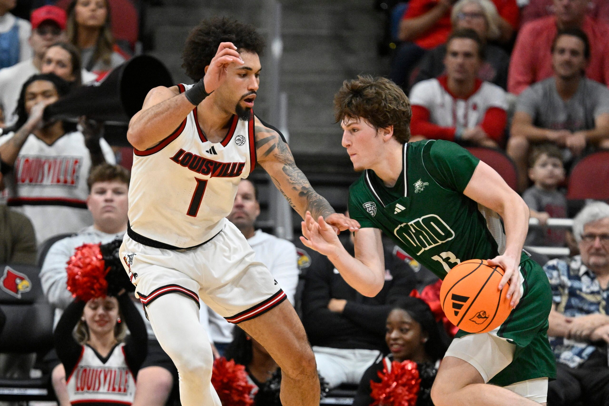 Nov 15, 2025; Louisville, Kentucky, USA;  Ohio Bobcats guard Jackson Paveletzke (13) dribbles against Louisville Cardinals guard J'Vonne Hadley (1) during the second half at KFC Yum! Center. Louisville defeated Ohio 106-81. Mandatory Credit: Jamie Rhodes-Imagn Images