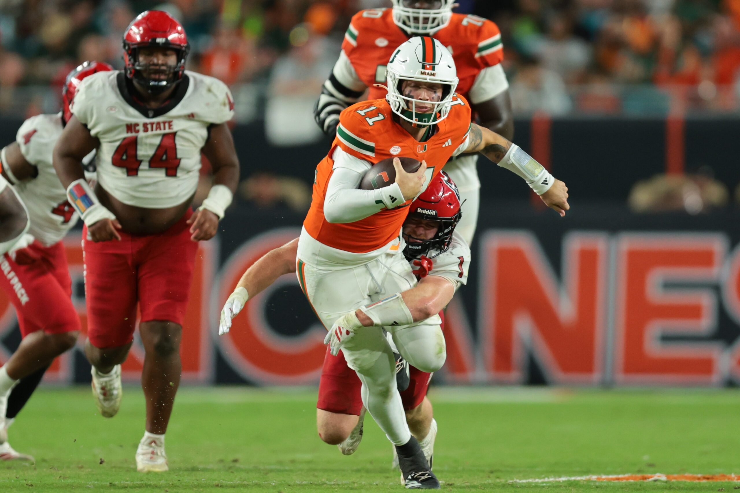 Nov 15, 2025; Miami Gardens, Florida, USA; Miami Hurricanes quarterback Carson Beck (11) carries the football against NC State Wolfpack linebacker Caden Fordham (1) during the third quarter at Hard Rock Stadium. Mandatory Credit: Sam Navarro-Imagn Images
