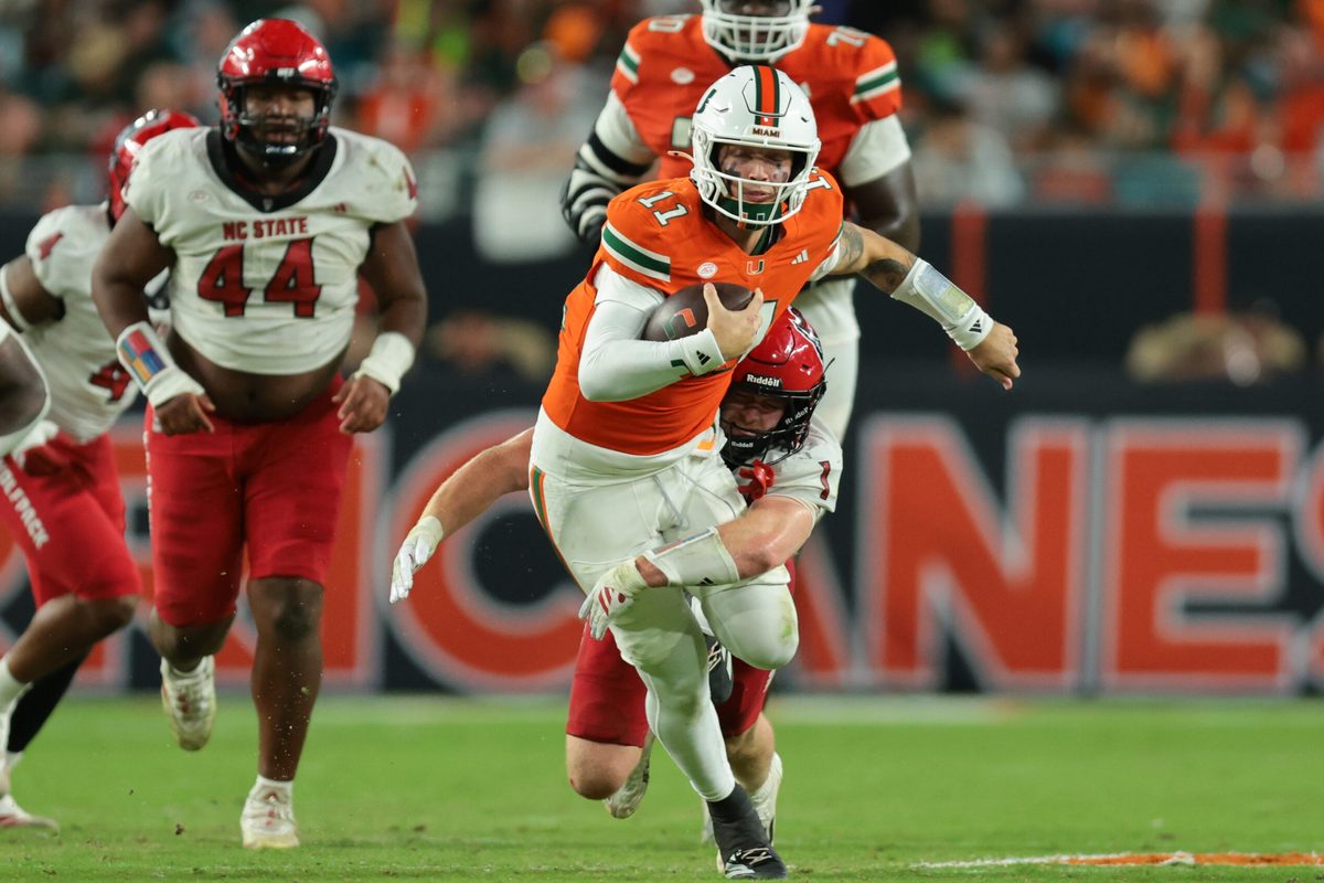 Nov 15, 2025; Miami Gardens, Florida, USA; Miami Hurricanes quarterback Carson Beck (11) carries the football against NC State Wolfpack linebacker Caden Fordham (1) during the third quarter at Hard Rock Stadium. Mandatory Credit: Sam Navarro-Imagn Images