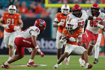 Nov 15, 2025; Miami Gardens, Florida, USA; Miami Hurricanes running back Girard Pringle Jr. (22) carries the football against NC State Wolfpack defensive back Asaad Brown Jr. (26) during the third quarter at Hard Rock Stadium. Mandatory Credit: Sam Navarro-Imagn Images