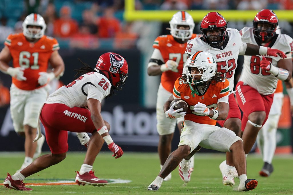 Nov 15, 2025; Miami Gardens, Florida, USA; Miami Hurricanes running back Girard Pringle Jr. (22) carries the football against NC State Wolfpack defensive back Asaad Brown Jr. (26) during the third quarter at Hard Rock Stadium. Mandatory Credit: Sam Navarro-Imagn Images
