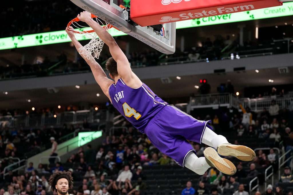 Nov 15, 2025; Milwaukee, Wisconsin, USA; Los Angeles Lakers guard Dalton Knecht (4) hangs from the rim following a slam dunk during the fourth quarter against the Milwaukee Bucks at Fiserv Forum. Mandatory Credit: Jeff Hanisch-Imagn Images