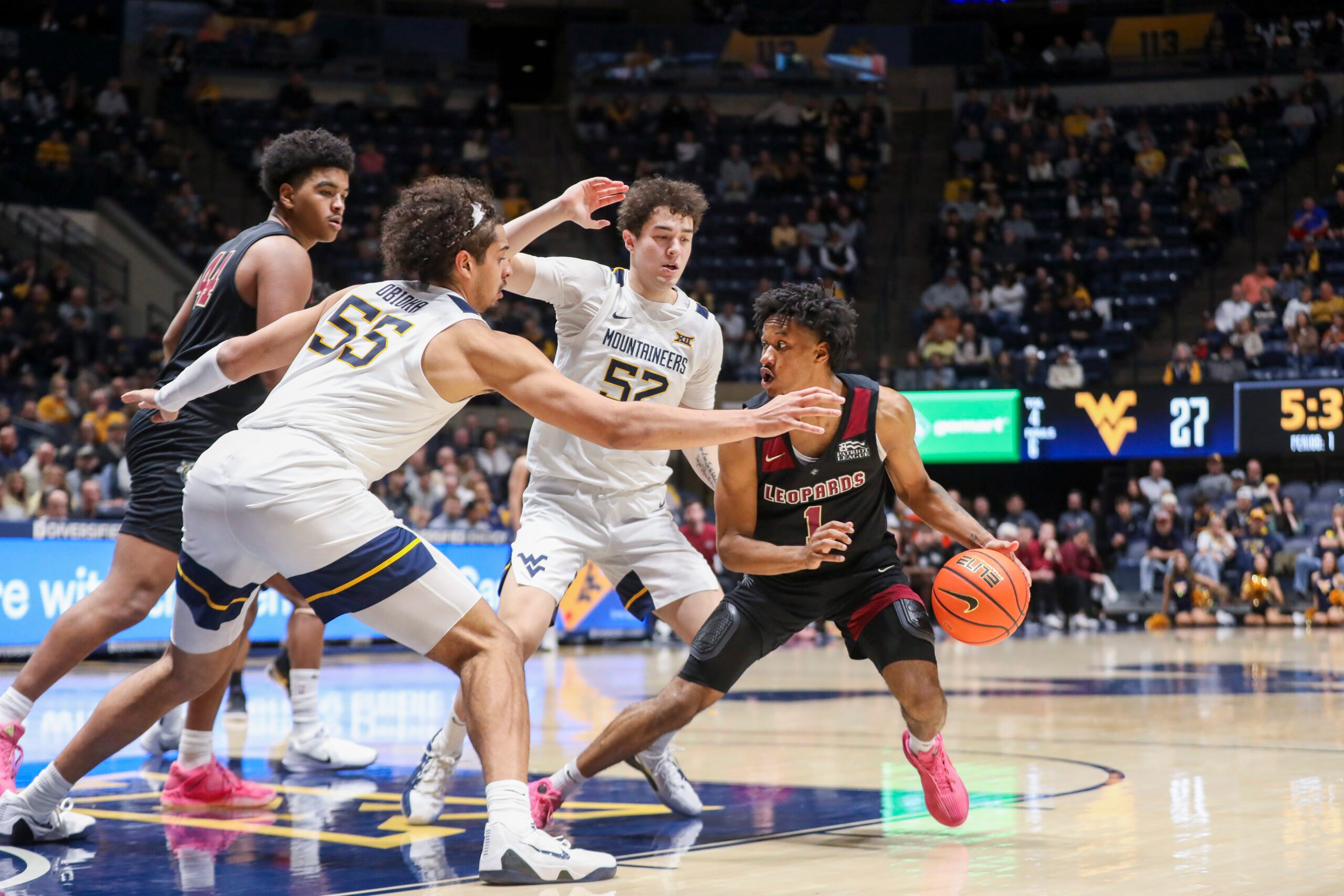 Nov 17, 2025; Morgantown, West Virginia, USA; Lafayette Leopards guard Caleb Williams (1) dribbles in the lane against West Virginia Mountaineers center Harlan Obioha (55) and West Virginia Mountaineers guard Treysen Eaglestaff (52) during the first half at WVU Coliseum. Mandatory Credit: Ben Queen-Imagn Images