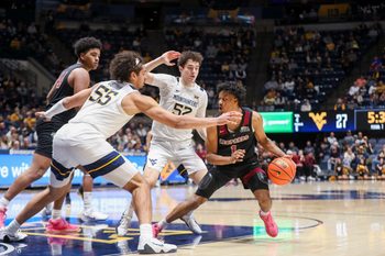 Nov 17, 2025; Morgantown, West Virginia, USA; Lafayette Leopards guard Caleb Williams (1) dribbles in the lane against West Virginia Mountaineers center Harlan Obioha (55) and West Virginia Mountaineers guard Treysen Eaglestaff (52) during the first half at WVU Coliseum. Mandatory Credit: Ben Queen-Imagn Images