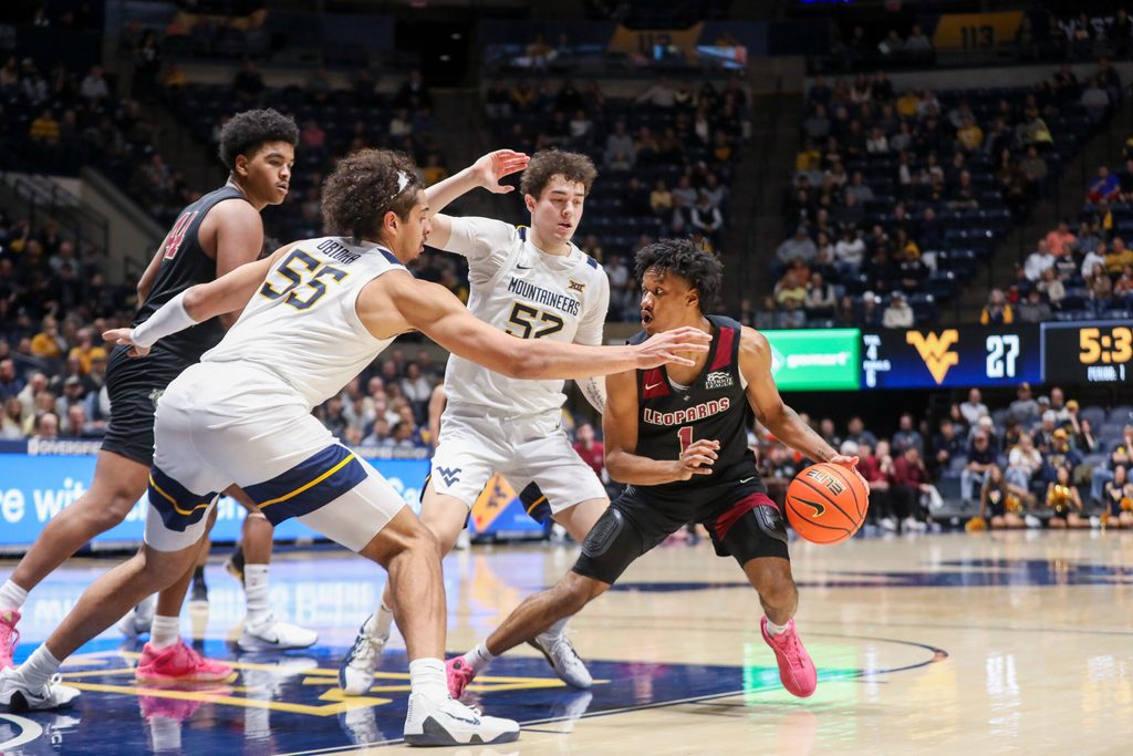 Nov 17, 2025; Morgantown, West Virginia, USA; Lafayette Leopards guard Caleb Williams (1) dribbles in the lane against West Virginia Mountaineers center Harlan Obioha (55) and West Virginia Mountaineers guard Treysen Eaglestaff (52) during the first half at WVU Coliseum. Mandatory Credit: Ben Queen-Imagn Images