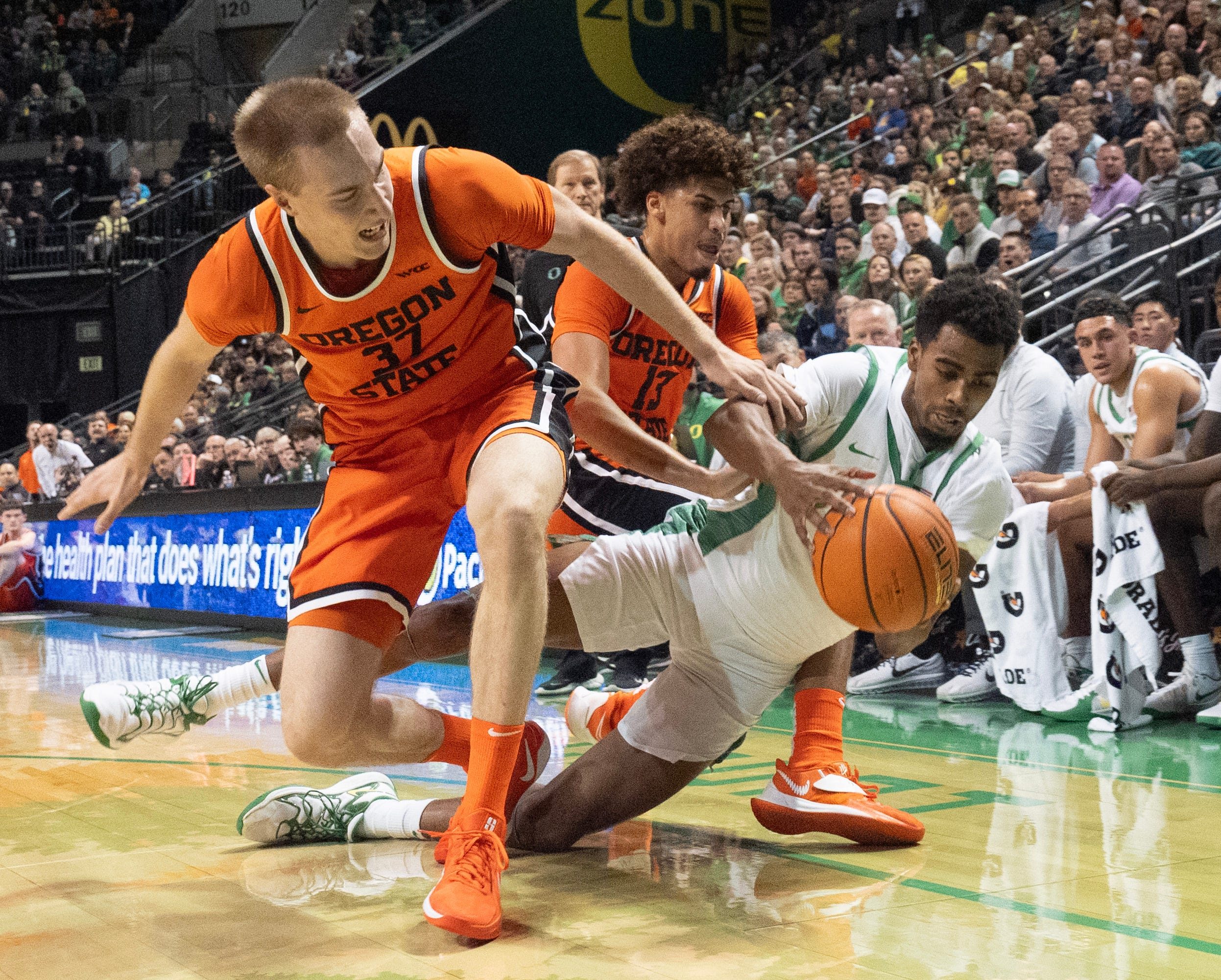 Oregon State’s Olavi Suutela, left, and Isaiah Sy battle Oregon’s Sean Stewart for a loose ball during the first half at Matthew Knight Arena in Eugene Nov. 17, 2025.