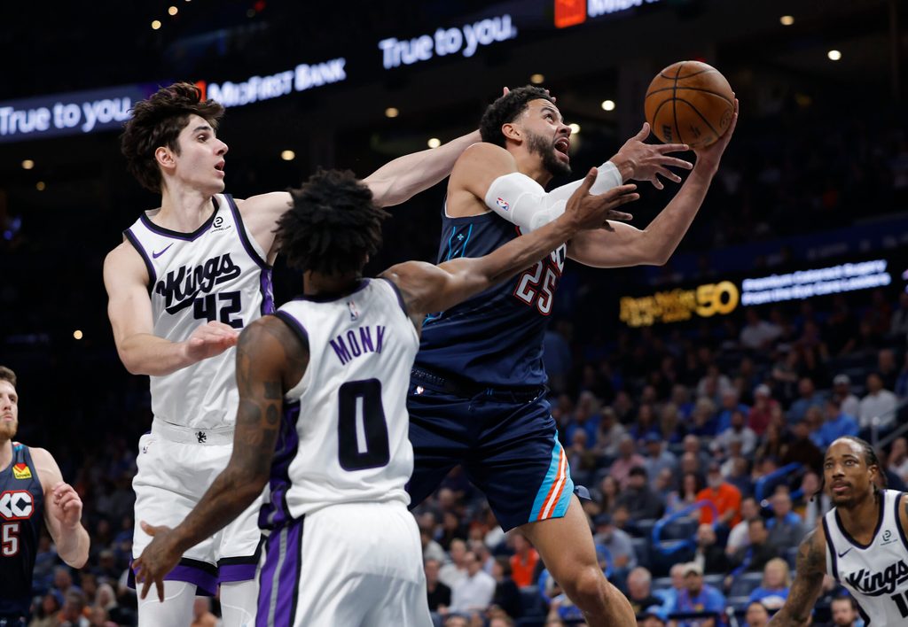 Nov 19, 2025; Oklahoma City, Oklahoma, USA; Oklahoma City Thunder guard Ajay Mitchell (25) goes up for a basket between Sacramento Kings center Maxime Raynaud (42) and guard Malik Monk (0) during the second half at Paycom Center. Mandatory Credit: Alonzo Adams-Imagn Images