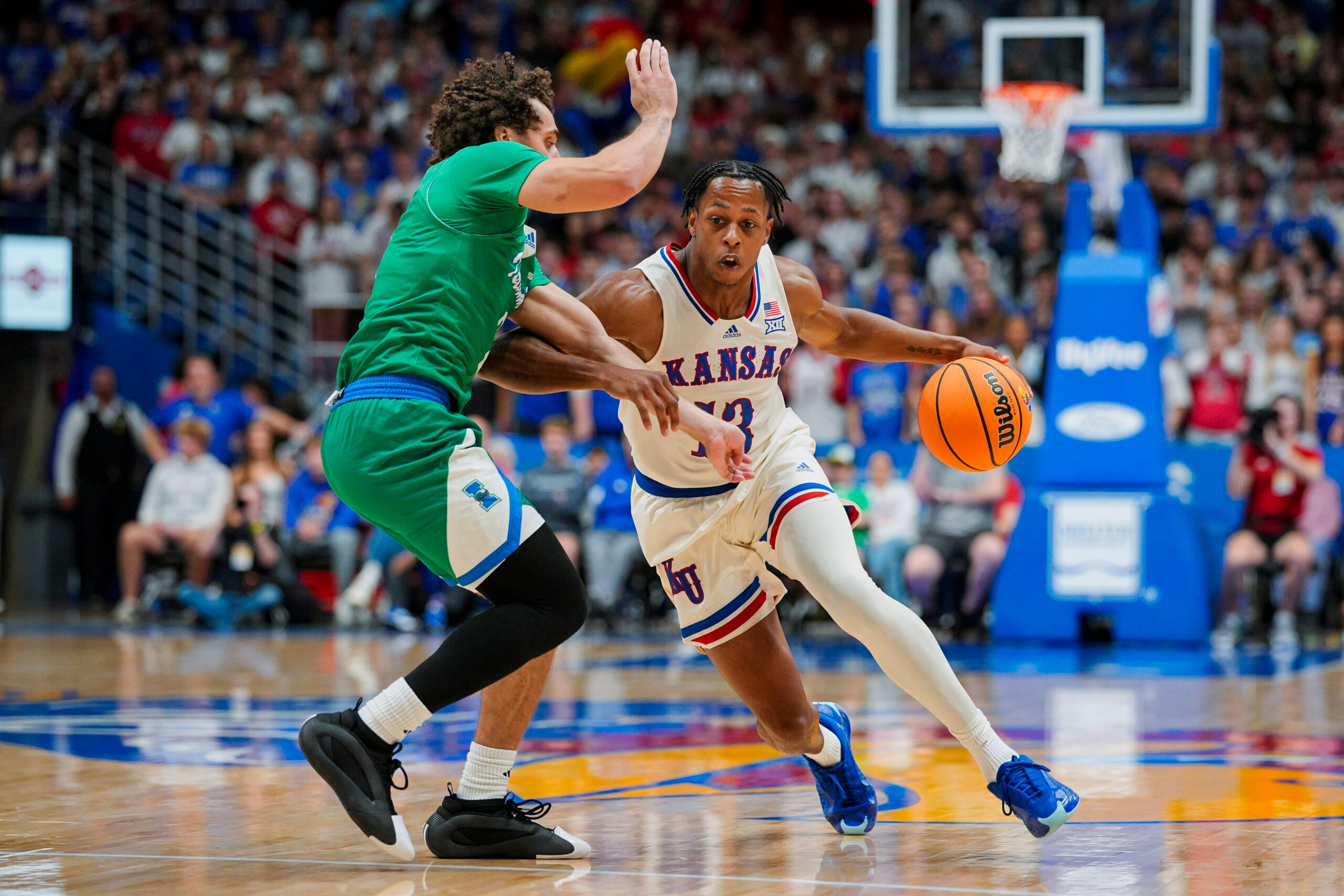 Nov 11, 2025; Lawrence, Kansas, USA; Kansas Jayhawks guard Elmarko Jackson (13) drives against Texas A&M-Corpus Christi Islanders forward Jaden Haire (11) during the first half at Allen Fieldhouse. Mandatory Credit: Jay Biggerstaff-Imagn Images