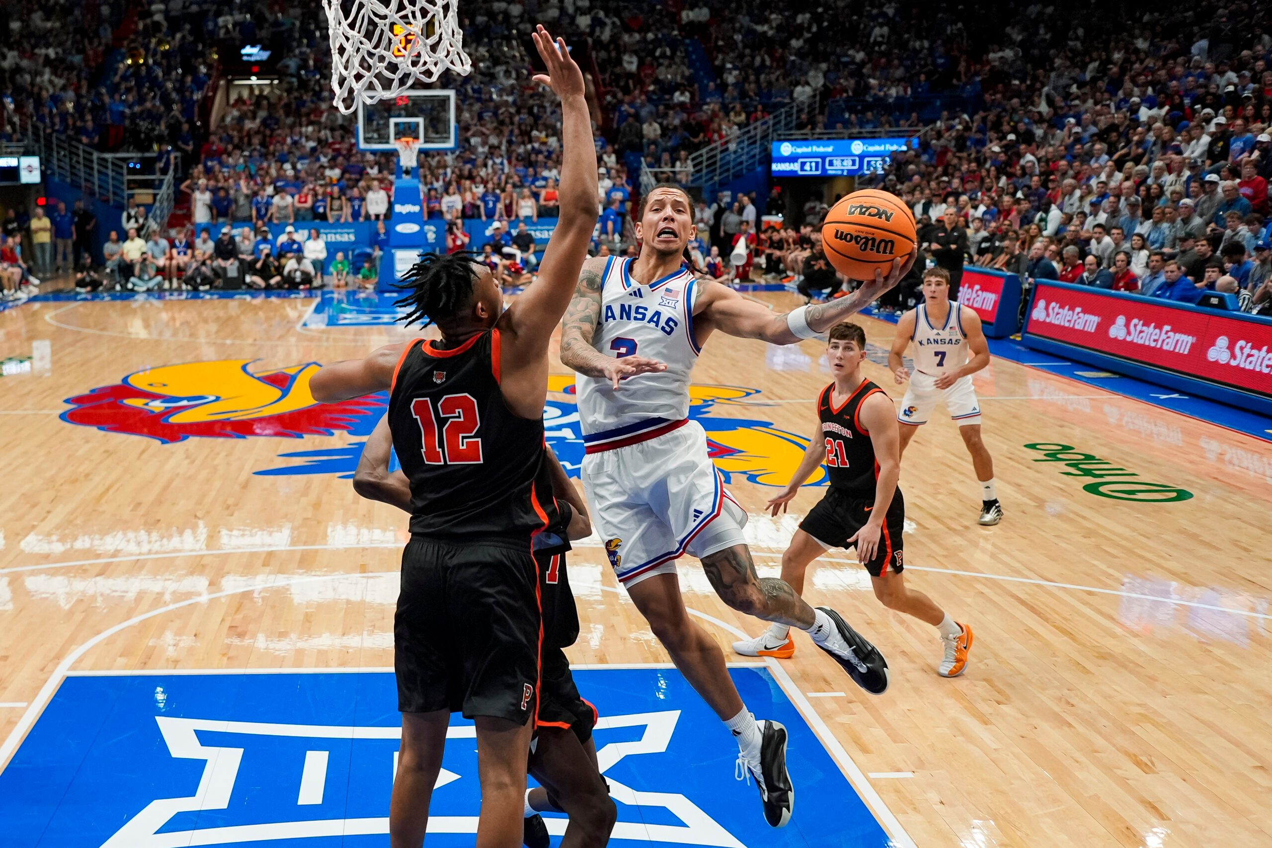Nov 15, 2025; Lawrence, Kansas, USA; Kansas Jayhawks guard Tre White (3) shoots against Princeton Tigers forward Jacob Huggins (12) and forward Malik Abdullahi (7) during the second half at Allen Fieldhouse. Mandatory Credit: Jay Biggerstaff-Imagn Images