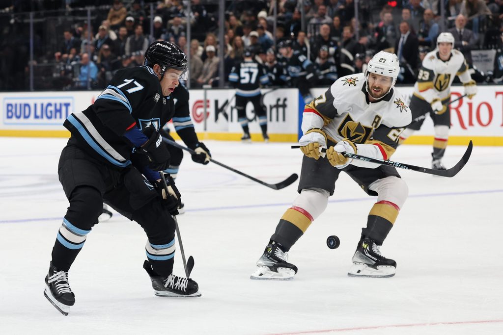 Nov 20, 2025; Salt Lake City, Utah, USA; Utah Mammoth right wing JJ Peterka (77) and Vegas Golden Knights defenseman Shea Theodore (27) battle for the puck during the first period at Delta Center. Mandatory Credit: Rob Gray-Imagn Images