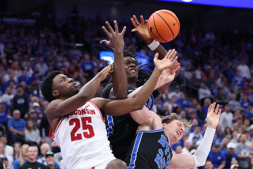 Nov 21, 2025; Salt Lake City, Utah, USA; Wisconsin Badgers guard John Blackwell (25) fights for the ball against BYU Cougars forward Khadim Mboup (7) and guard Dawson Baker (25) during the second half at Delta Center. Mandatory Credit: Rob Gray-Imagn Images