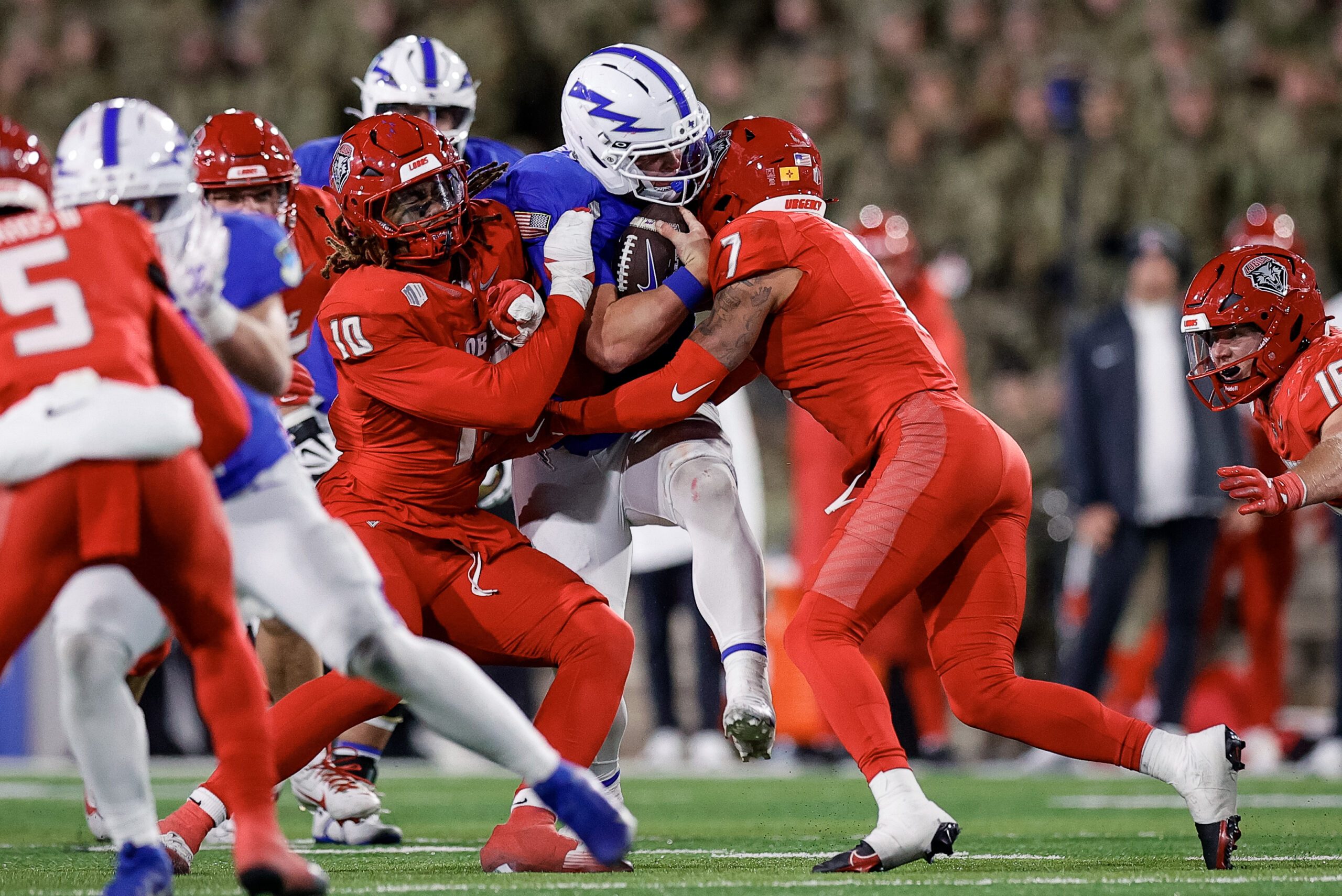 Nov 22, 2025; Colorado Springs, Colorado, USA; Air Force Falcons quarterback Kemper Hodges (4) is sacked by New Mexico Lobos defensive end Darren Agu (10) and safety Tavian Combs (7) in the third quarter at Falcon Stadium. Mandatory Credit: Isaiah J. Downing-Imagn Images