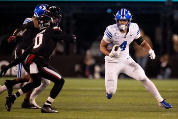 BYU Cougars running back LJ Martin (4) runs the ball as Cincinnati Bearcats cornerback Matthew McDoom (0) defends in the third quarter of the NCAA football game at Nippert Stadium in Cincinnati on Nov. 22, 2025.