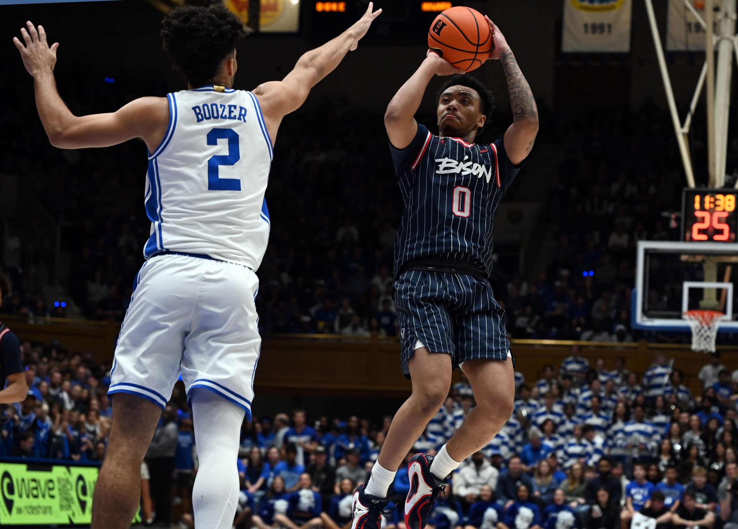 Nov 23, 2025; Durham, North Carolina, USA;  Howard Bison guard Isaiah Brown (0) shoots over Duke Blue Devils guard Cayden Boozer (2) during the first half at Cameron Indoor Stadium. Mandatory Credit: Rob Kinnan-Imagn Images