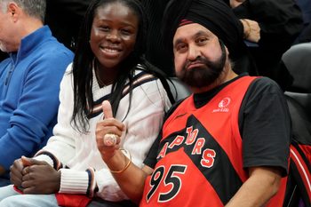 Nov 24, 2025; Toronto, Ontario, CAN; Canadian tennis star Victoria Mboko (left) sits court side with Toronto Raptors superfan Nav Bhatia (right) during a game between the Cleveland Cavaliers and Toronto Raptors during the second half at Scotiabank Arena. Mandatory Credit: John E. Sokolowski-Imagn Images