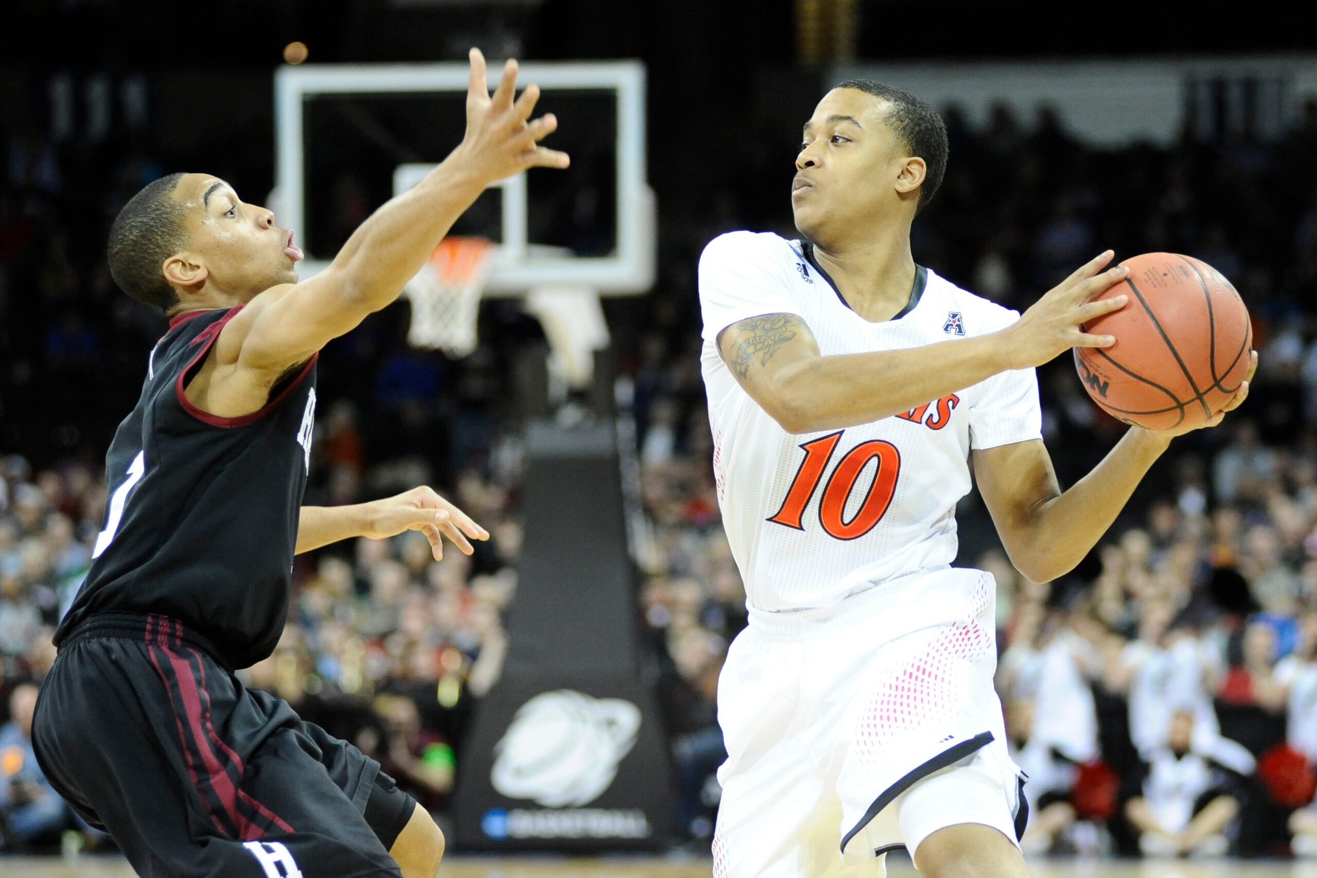 Mar 20, 2014; Spokane, WA, USA; Cincinnati Bearcats guard Troy Caupain (10) is defended by Harvard Crimson guard Siyani Chambers (1, left) in the first half of a men's college basketball game during the second round of the 2014 NCAA Tournament at Veterans Memorial Arena. Mandatory Credit: James Snook-Imagn Images