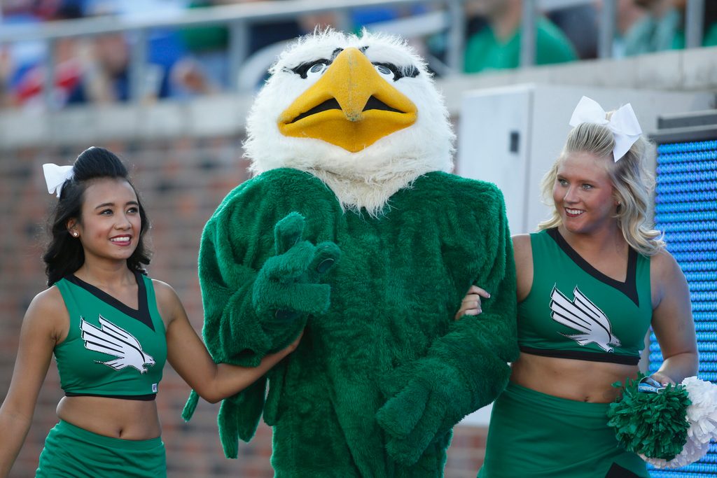 Sep 12, 2015; Dallas, TX, USA; North Texas Mean Green mascot Scrappy the Eagle walks with two cheerleaders during the game against the Southern Methodist Mustangs at Gerald J. Ford Stadium. Southern Methodist won 31-13. Mandatory Credit: Tim Heitman-Imagn Images