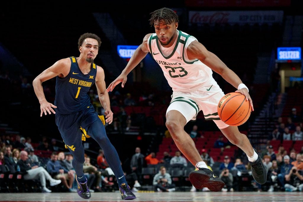Nov 25, 2022; Portland, Oregon, USA; Portland State Vikings guard Jorell Saterfield (23) drives to the basket past West Virginia Mountaineers forward Emmitt Matthews Jr. (1) during the first half at Moda Center. Mandatory Credit: Troy Wayrynen-Imagn Images