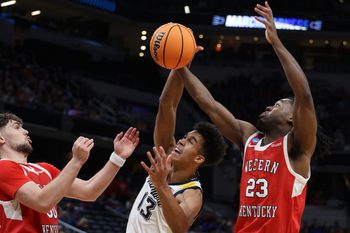 Mar 22, 2024; Indianapolis, IN, USA; Western Kentucky Hilltoppers guard Enoch Kalambay (23) and guard Teagan Moore (30) defend against Marquette Golden Eagles forward Oso Ighodaro (13) in the second half in the first round of the 2024 NCAA Tournament at Gainbridge FieldHouse. Mandatory Credit: Trevor Ruszkowski-Imagn Images