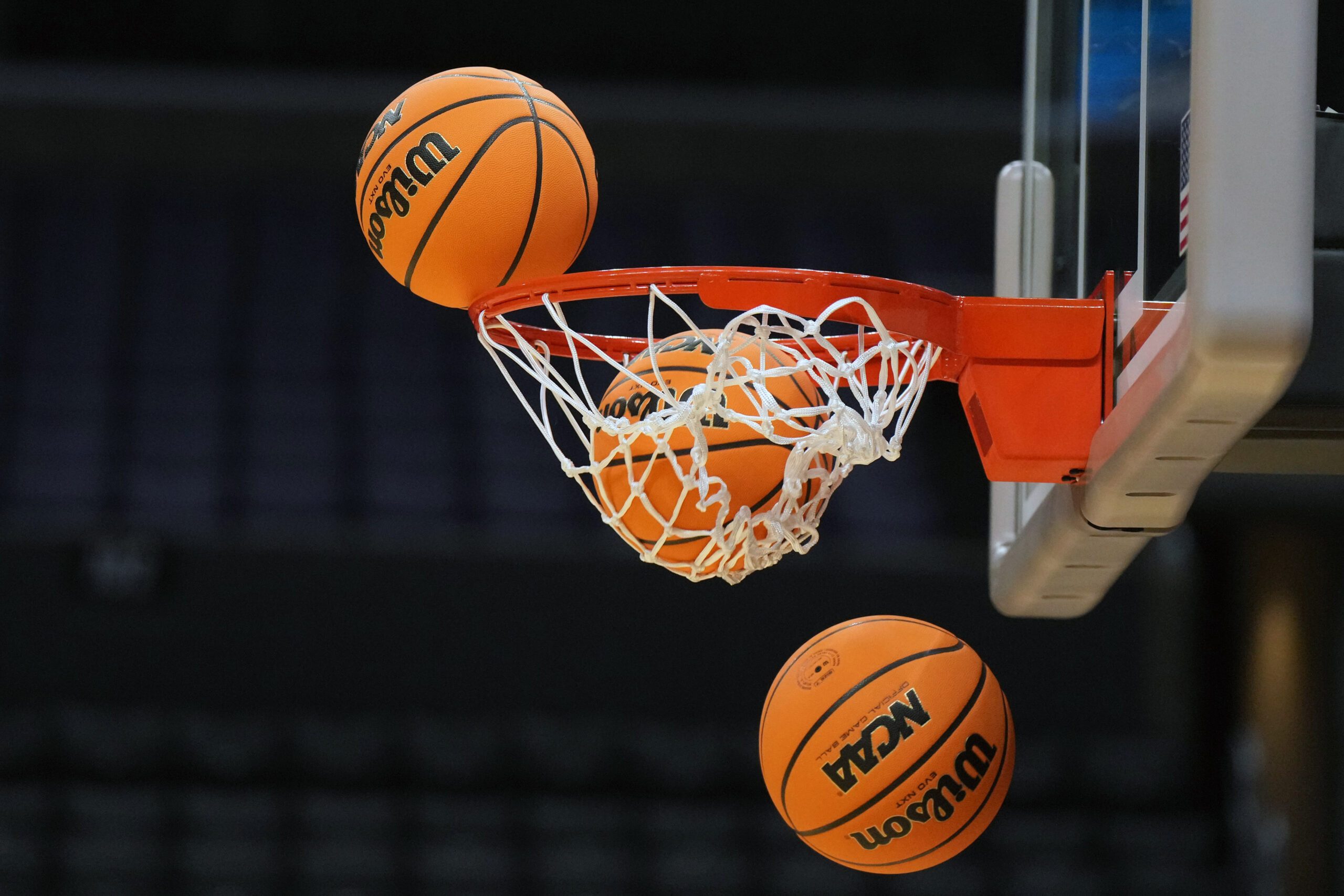 Mar 27, 2024; Los Angeles, CA, USA; Wilson official Evo NXT game basketballs with March Madness and Elite 8 and Sweet logo approaches the rim and net at Crypto.com Arena. Mandatory Credit: Kirby Lee-Imagn Images