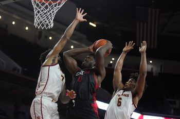 Dec 18, 2024; Los Angeles, California, USA; Cal State Northridge Matadors forward Festus Ndumanya (6) shoots the ball against Southern California Trojans guard Wesley Yates III (6)and guard Chibuzo Agbo (7) at Galen Center. Mandatory Credit: Kirby Lee-Imagn Images