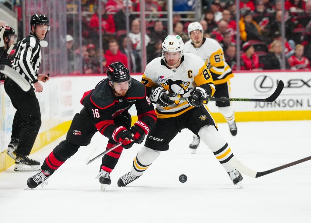 Jan 5, 2025; Raleigh, North Carolina, USA; Carolina Hurricanes center Jack Roslovic (96) and Pittsburgh Penguins center Sidney Crosby (87) battle over the puck during the third period at Lenovo Center. Mandatory Credit: James Guillory-Imagn Images