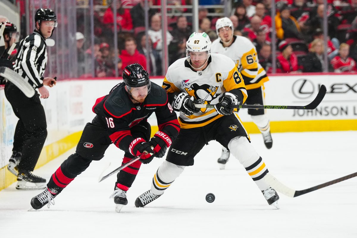 Jan 5, 2025; Raleigh, North Carolina, USA; Carolina Hurricanes center Jack Roslovic (96) and Pittsburgh Penguins center Sidney Crosby (87) battle over the puck during the third period at Lenovo Center. Mandatory Credit: James Guillory-Imagn Images