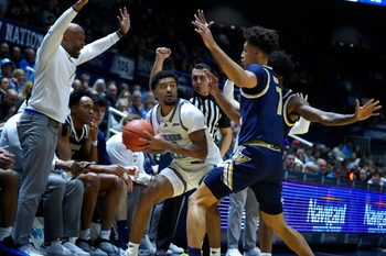 Jamarques Lawrence of URI looks for a way out of the double defense of Dayan Nessah and Christian Jones of George Washington.