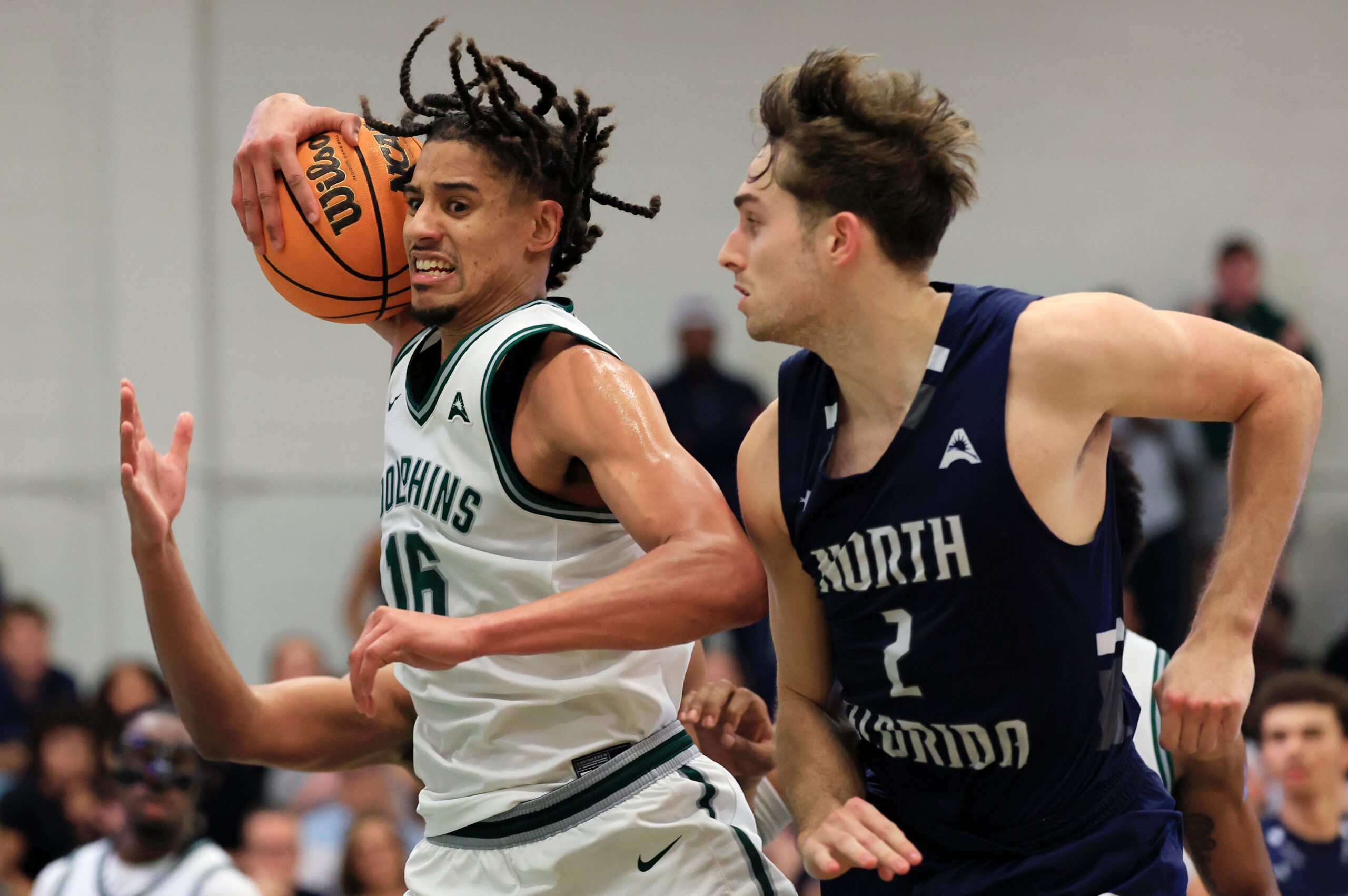 Jacksonville Dolphins forward Zimi Nwokeji (16) grabs a rebound as North Florida Ospreys guard Nate Lliteras (2) looks on during the second half of an NCAA men’s basketball matchup Saturday, Feb. 1, 2025 at Jacksonville University in Jacksonville, Fla. UNF held off a late rally from JU defeating them 81-78. [Corey Perrine/Florida Times-Union]