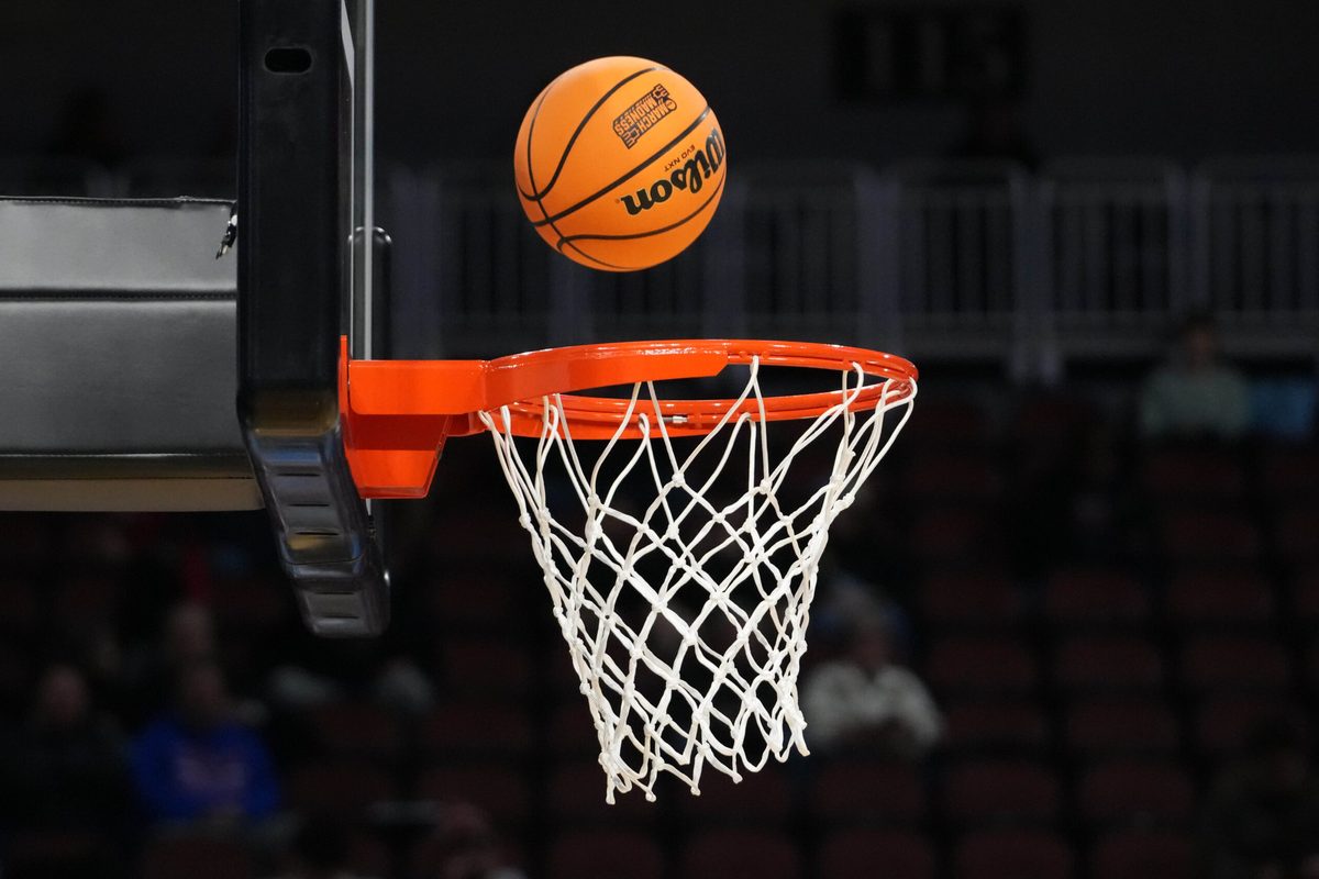 Mar 19, 2025; Wichita, KS, USA; A Wilson official NCAA Evo NXT basketball with the March Madness logo approaches the rim and the net at Intrust Bank Arena. Mandatory Credit: Kirby Lee-Imagn Images
