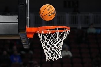 Mar 19, 2025; Wichita, KS, USA; A Wilson official NCAA Evo NXT basketball with the March Madness logo approaches the rim and the net at Intrust Bank Arena. Mandatory Credit: Kirby Lee-Imagn Images