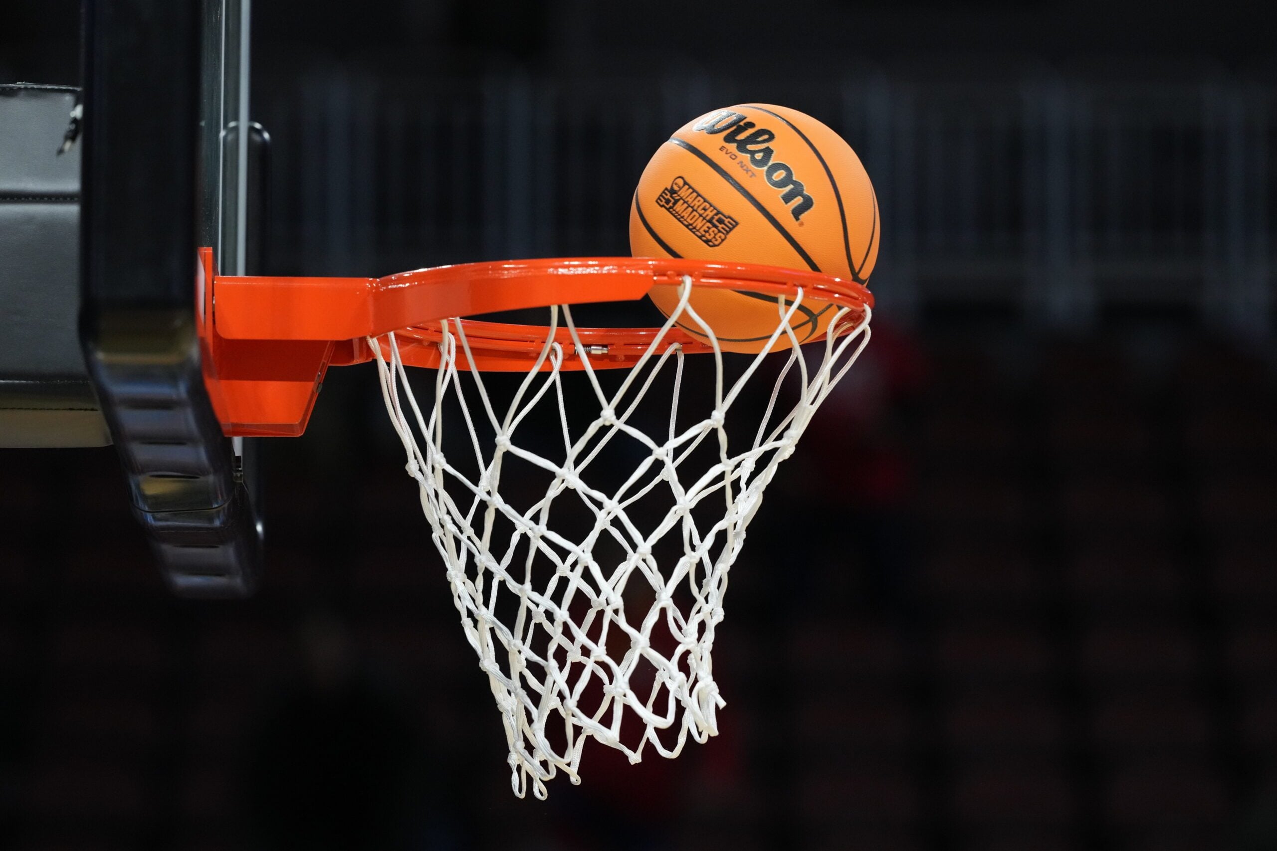 Mar 19, 2025; Wichita, KS, USA; A Wilson Evo NXT official basketball with March Madness logo approaches the rim and the net at Intrust Bank Arena. Mandatory Credit: Kirby Lee-Imagn Images