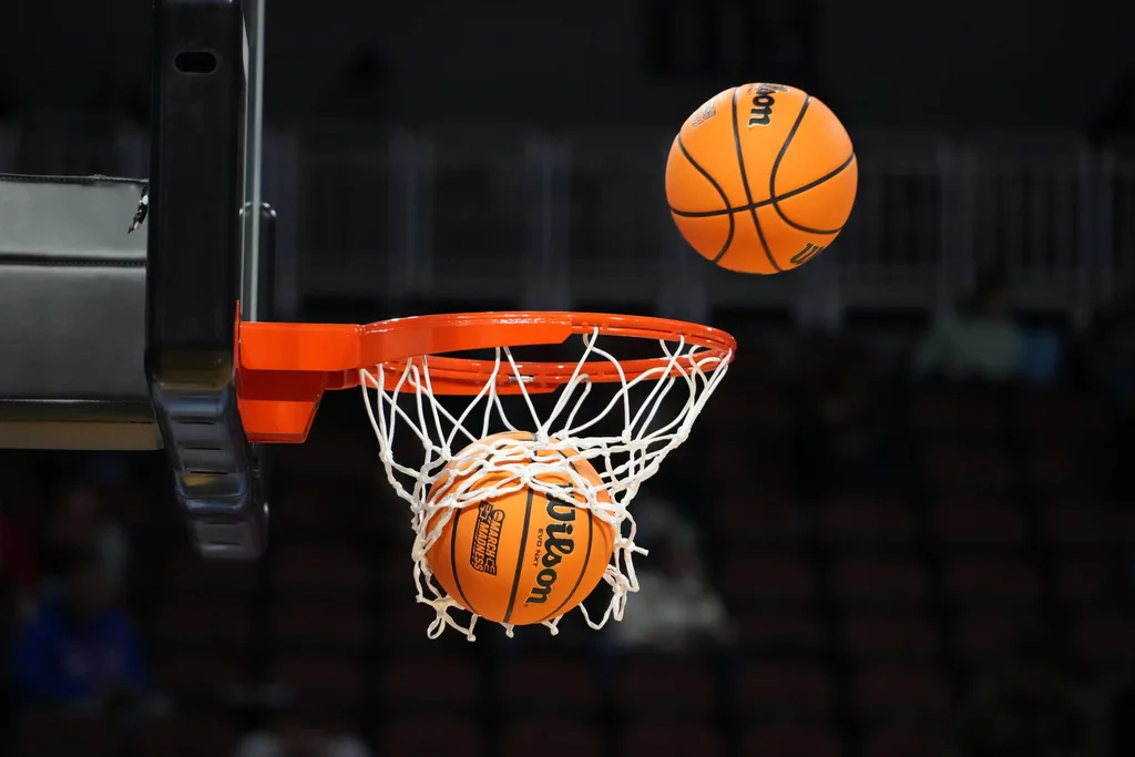 Mar 19, 2025; Wichita, KS, USA; Wilson Evo NXT official basketballs with March Madness logo approach the rim and the net at Intrust Bank Arena. Mandatory Credit: Kirby Lee-Imagn Images