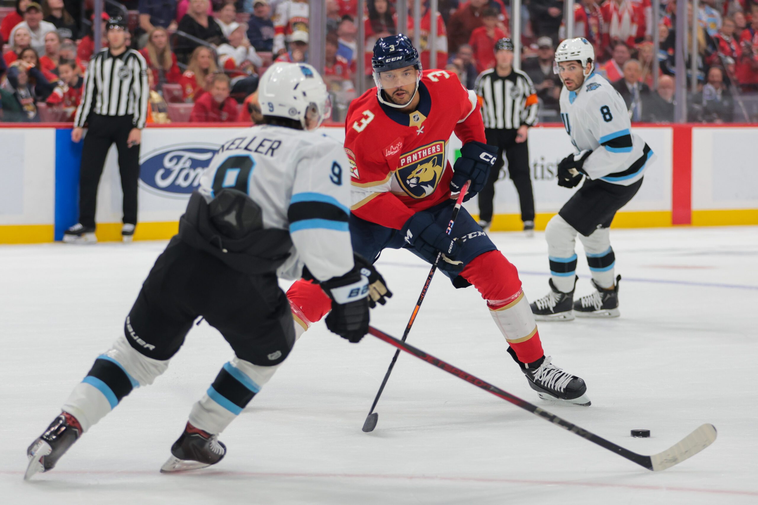 Mar 28, 2025; Sunrise, Florida, USA; Florida Panthers defenseman Seth Jones (3) moves the puck as Utah Hockey Club center Clayton Keller (9) defends during overtime at Amerant Bank Arena. Mandatory Credit: Sam Navarro-Imagn Images
