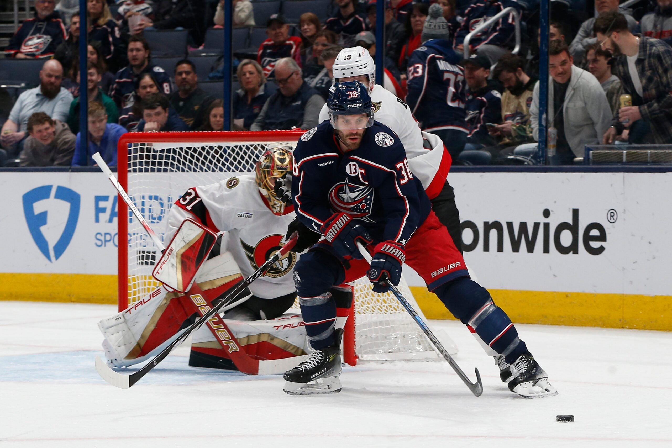 Apr 8, 2025; Columbus, Ohio, USA; Columbus Blue Jackets center Boone Jenner (38) passes the puck as Ottawa Senators left wing Claude Giroux (28) defends during the first period at Nationwide Arena. Mandatory Credit: Russell LaBounty-Imagn Images