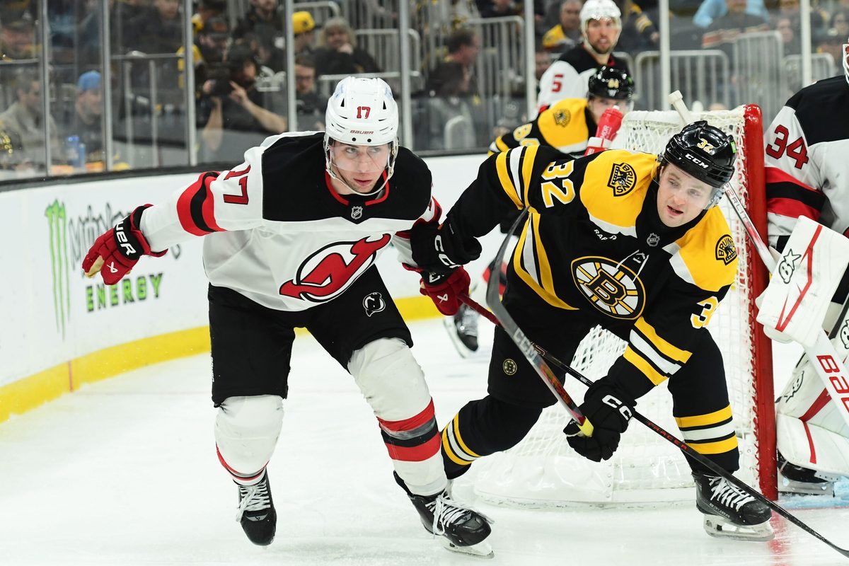 Apr 15, 2025; Boston, Massachusetts, USA; New Jersey Devils defenseman Simon Nemec (17) and Boston Bruins center John Farinacci (32) battle behind the goal during the third period at TD Garden. Mandatory Credit: Bob DeChiara-Imagn Images