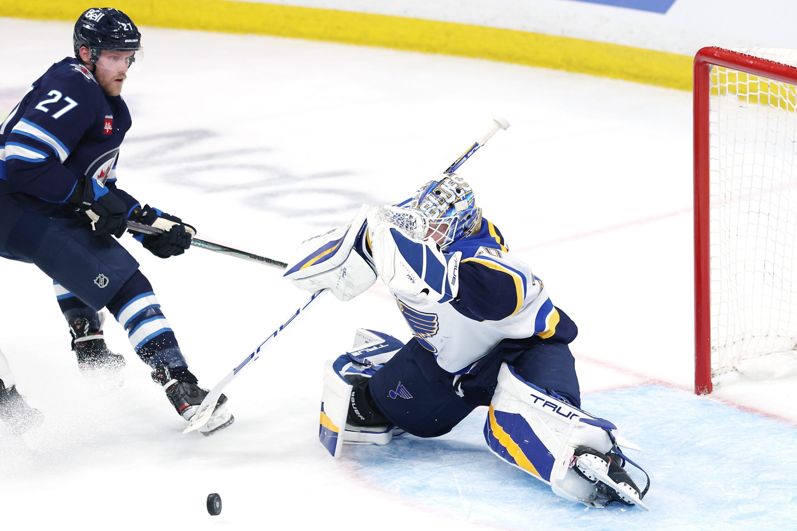 May 4, 2025; Winnipeg, Manitoba, CAN; St. Louis Blues goaltender Jordan Binnington (50) blocks a shot by Winnipeg Jets left wing Nikolaj Ehlers (27) in first overtime in game seven of the first round of the 2025 Stanley Cup Playoffs at Canada Life Centre. Mandatory Credit: James Carey Lauder-Imagn Images