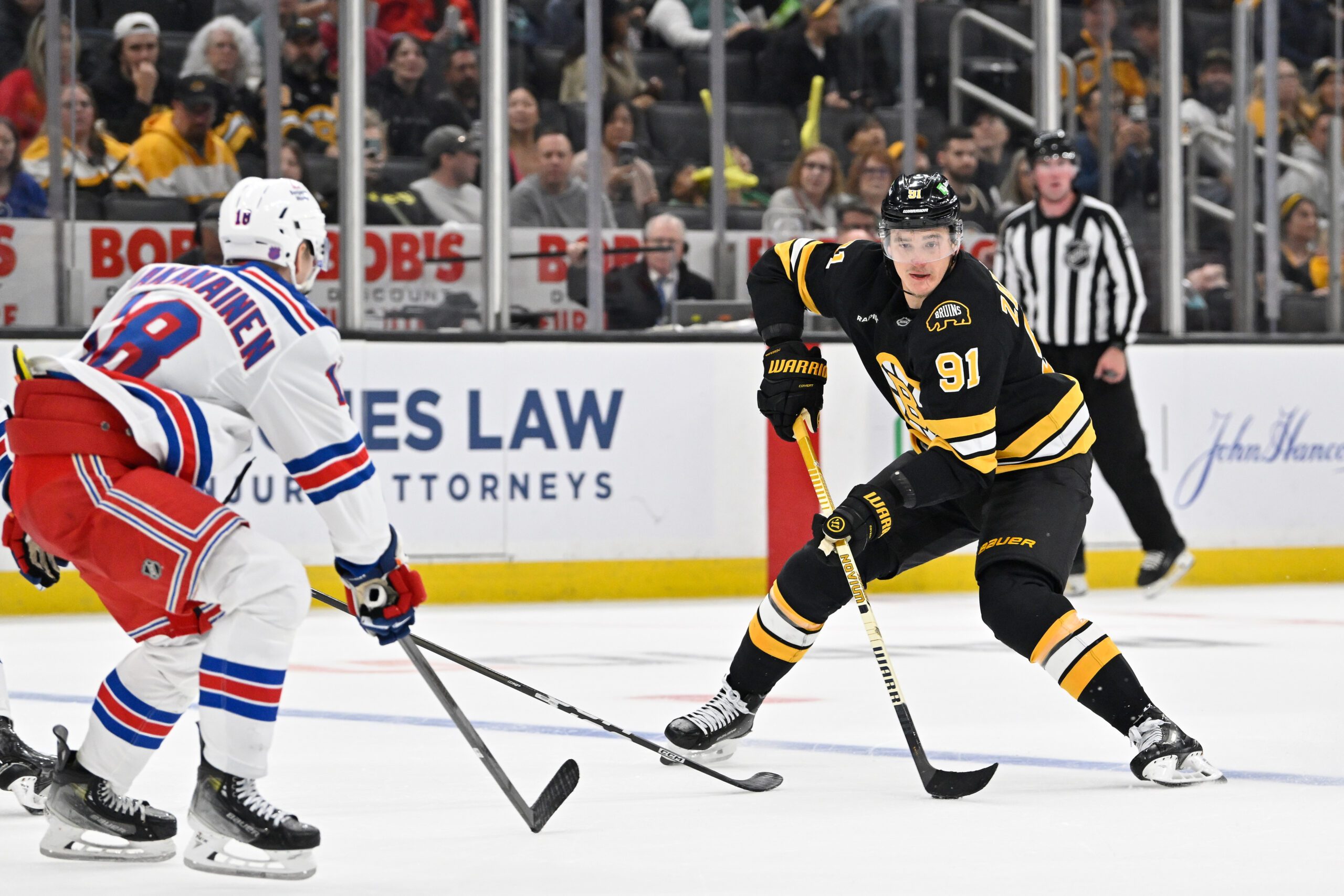 Oct 4, 2025; Boston, Massachusetts, USA; Boston Bruins defenseman Nikita Zadorov (91) plays the puck at the blue line against New York Rangers defenseman Urho Vaakanainen (18) during the third period period at TD Garden. Mandatory Credit: Eric Canha-Imagn Images