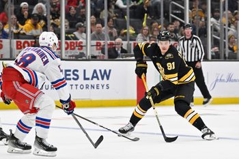 Oct 4, 2025; Boston, Massachusetts, USA; Boston Bruins defenseman Nikita Zadorov (91) plays the puck at the blue line against New York Rangers defenseman Urho Vaakanainen (18) during the third period period at TD Garden. Mandatory Credit: Eric Canha-Imagn Images