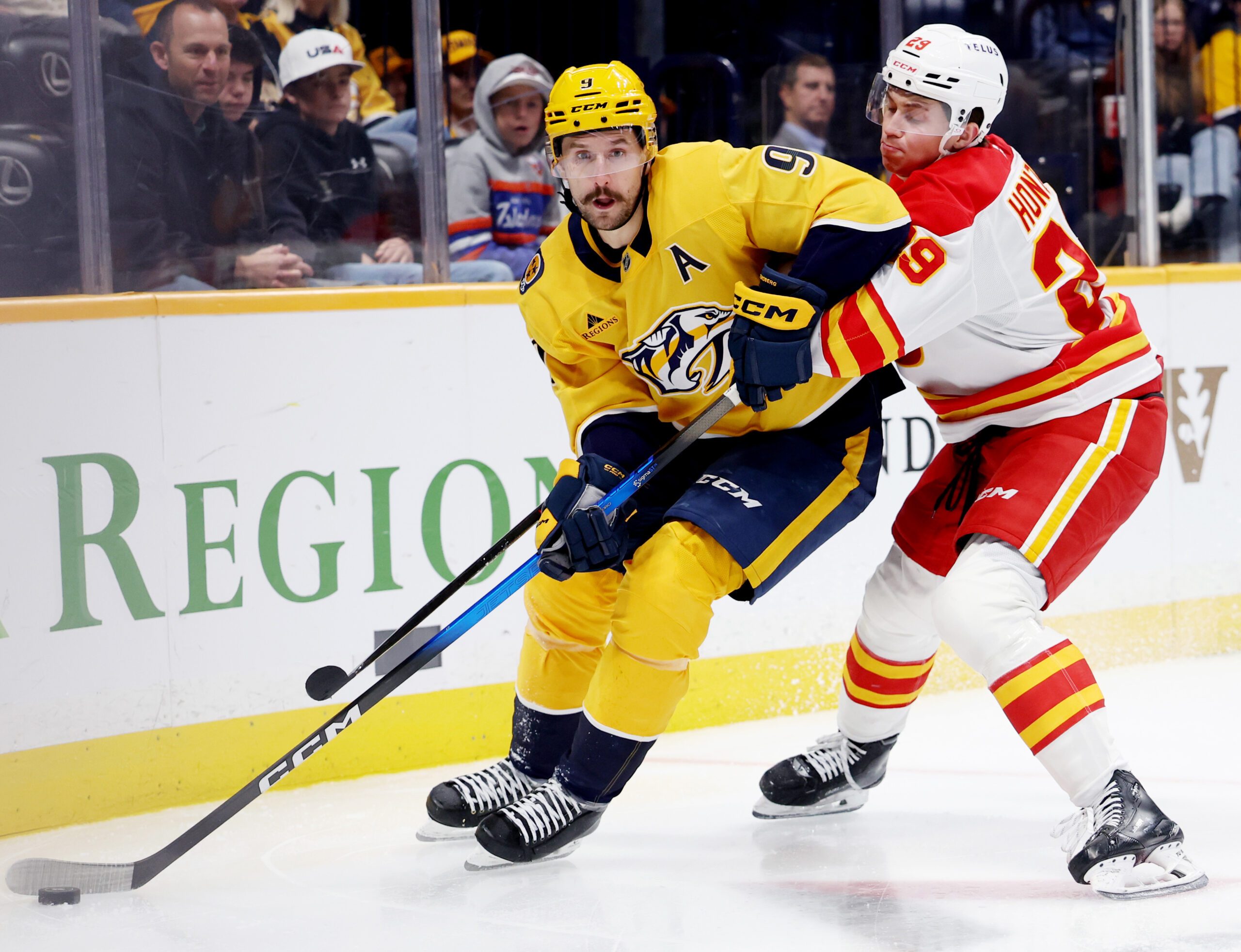 Nov 1, 2025; Nashville, Tennessee, USA; Nashville Predators left wing Filip Forsberg (9) moves the puck while being guarded by Calgary Flames left wing Samuel Honzek (29) during the third period at Bridgestone Arena. Mandatory Credit: Alan Poizner-Imagn Images