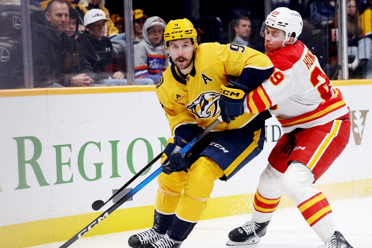 Nov 1, 2025; Nashville, Tennessee, USA; Nashville Predators left wing Filip Forsberg (9) moves the puck while being guarded by Calgary Flames left wing Samuel Honzek (29) during the third period at Bridgestone Arena. Mandatory Credit: Alan Poizner-Imagn Images