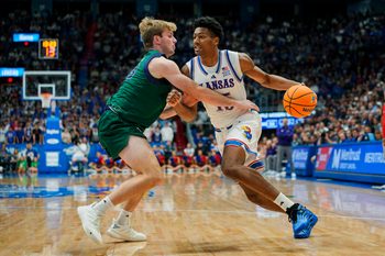 Nov 3, 2025; Lawrence, Kansas, USA; Kansas Jayhawks forward Bryson Tiller (15) drives against Green Bay Phoenix guard Keegan van Kauwenberg (3) during the second half at Allen Fieldhouse. Mandatory Credit: Jay Biggerstaff-Imagn Images
