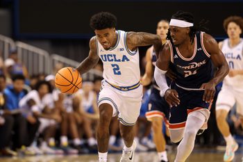 Nov 7, 2025; Los Angeles, California, USA;  UCLA Bruins guard Donovan Dent (2) dribbles the ball against Pepperdine Waves forward Javon Cooley (23) during the first half at Pauley Pavilion presented by Wescom Financial. Mandatory Credit: Kiyoshi Mio-Imagn Images