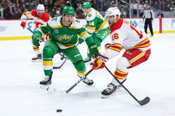 Nov 9, 2025; Saint Paul, Minnesota, USA; Calgary Flames center Morgan Frost (16) and Minnesota Wild defenseman Brock Faber (7) compete for the puck during the third period at Grand Casino Arena. Mandatory Credit: Matt Krohn-Imagn Images